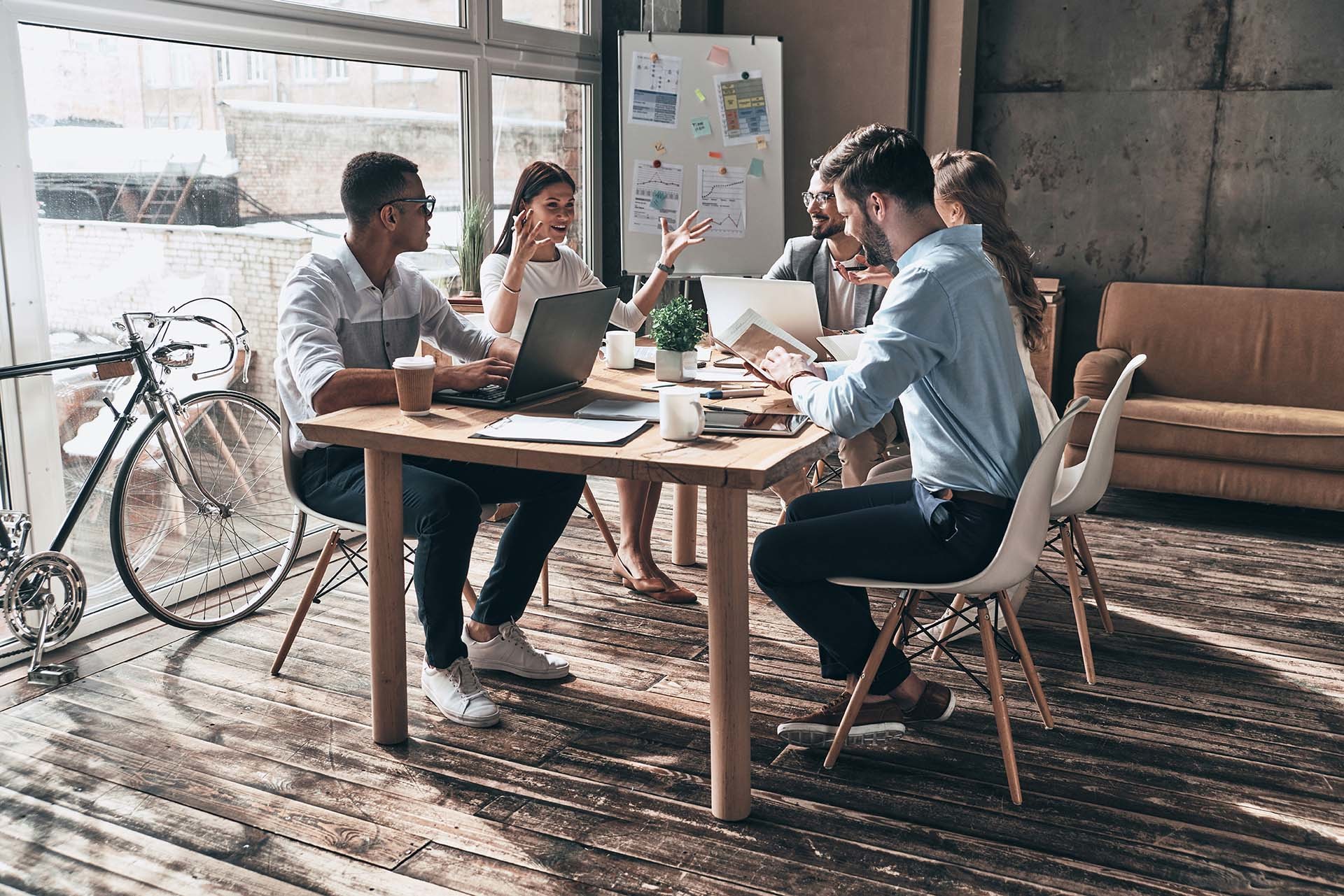 Ein kreatives Team in einem hellen, modernen Büro arbeitet zusammen – ein Beispiel für effektive Arbeitgeberkommunikation und kollaborative Markenstrategien, die N3W, eine Kreativagentur aus Charlottenberg, für Unternehmen entwickelt.
