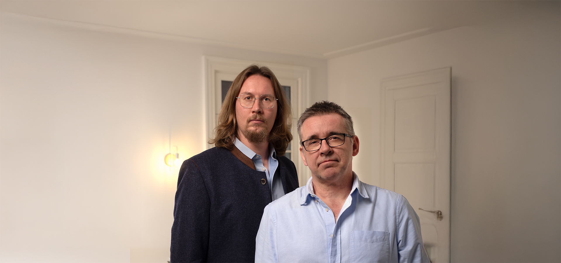 Zwei Männer, René Adam und Misi Hegedüs, in einem hellen, minimalistischen Innenraum, die die Kreativagentur N3W aus Charlottenberg repräsentieren, die sich auf verständliche Marken- und Kommunikationslösungen spezialisiert.